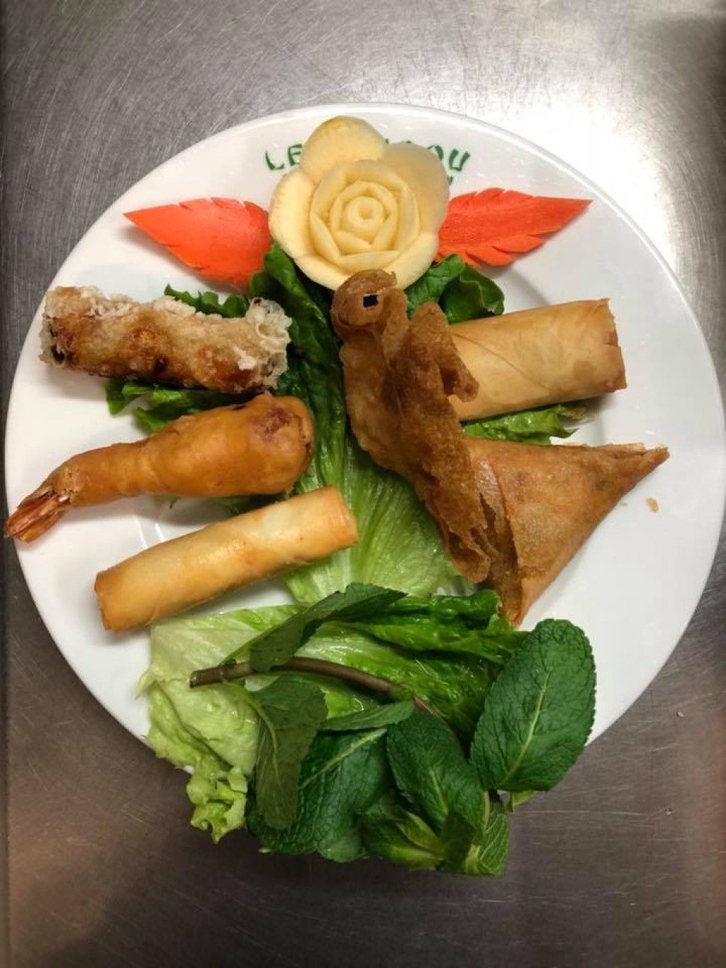 Une assiette de nems et de crevettes avec une décoration de carotte